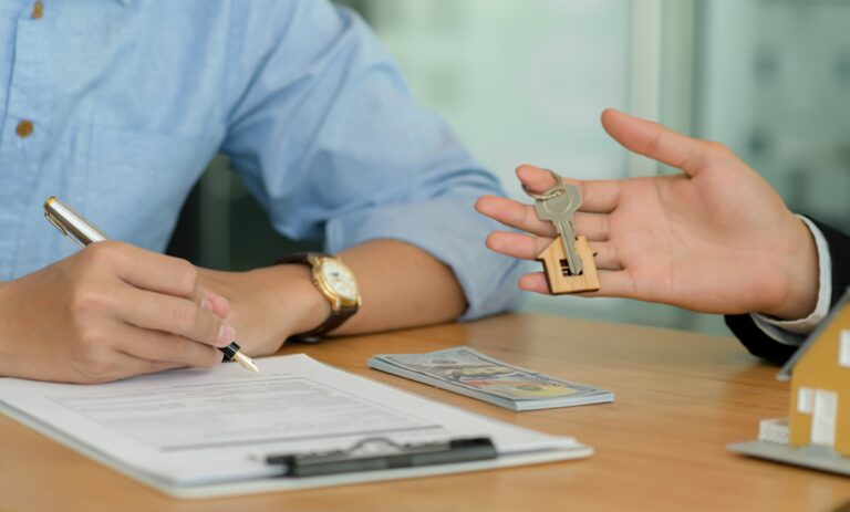 Close-up shot of Homebuyers signing home contracts and house brokers holding house key.